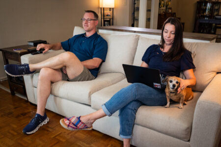 Sallye and her husband, Aaron, sitting on the couch while Sallye works on her computer