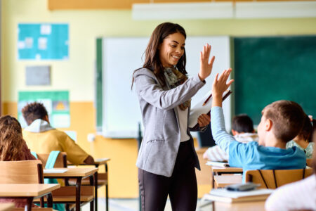 Happy dual language teacher receiving a high five from one of her elementary school students. 