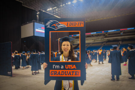 Sallye Barnes holding a UTSA sign that says "I did it! I'm a UTSA Graduate!"