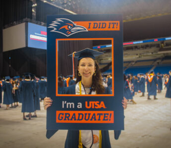 Sallye Barnes holding a UTSA sign that says "I did it! I'm a UTSA Graduate!"