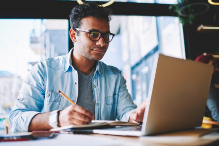 Man writing while looking at computer