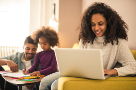 Mom working on laptop while family is in background