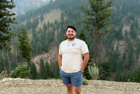 Mario Ortega standing on a cliff with Washington mountains behind him.
