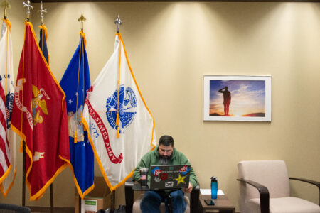 Man working on a laptop in front of flags.