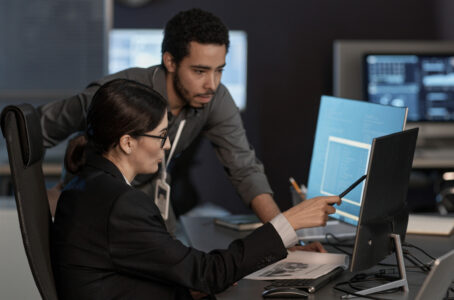 Side view portrait of two people pointing at computer screen