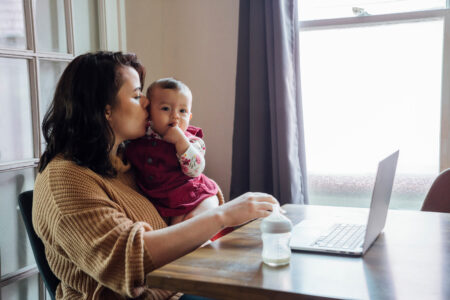 Mom working on laptop kissing baby