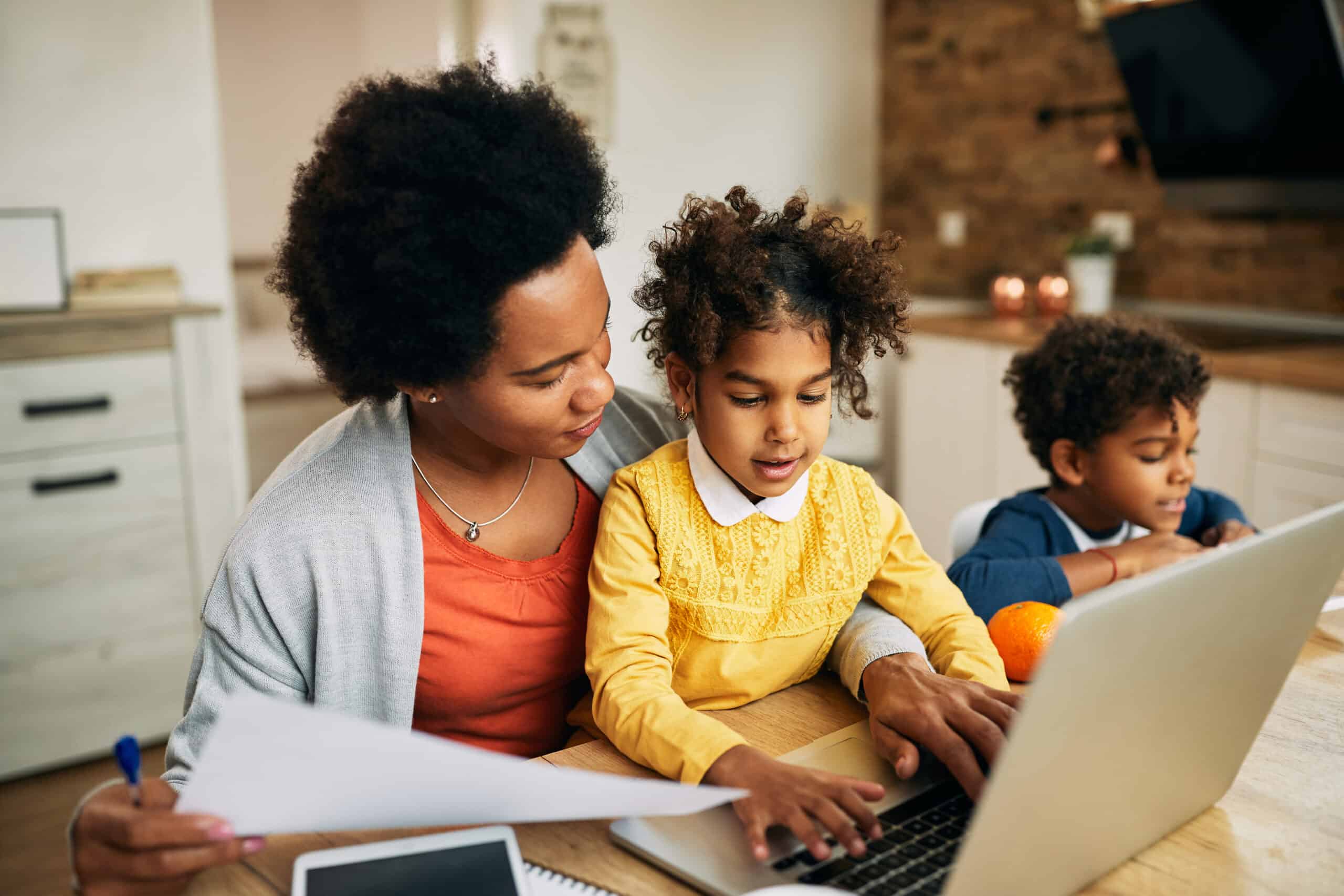 Woman working on a computer while taking care of two children