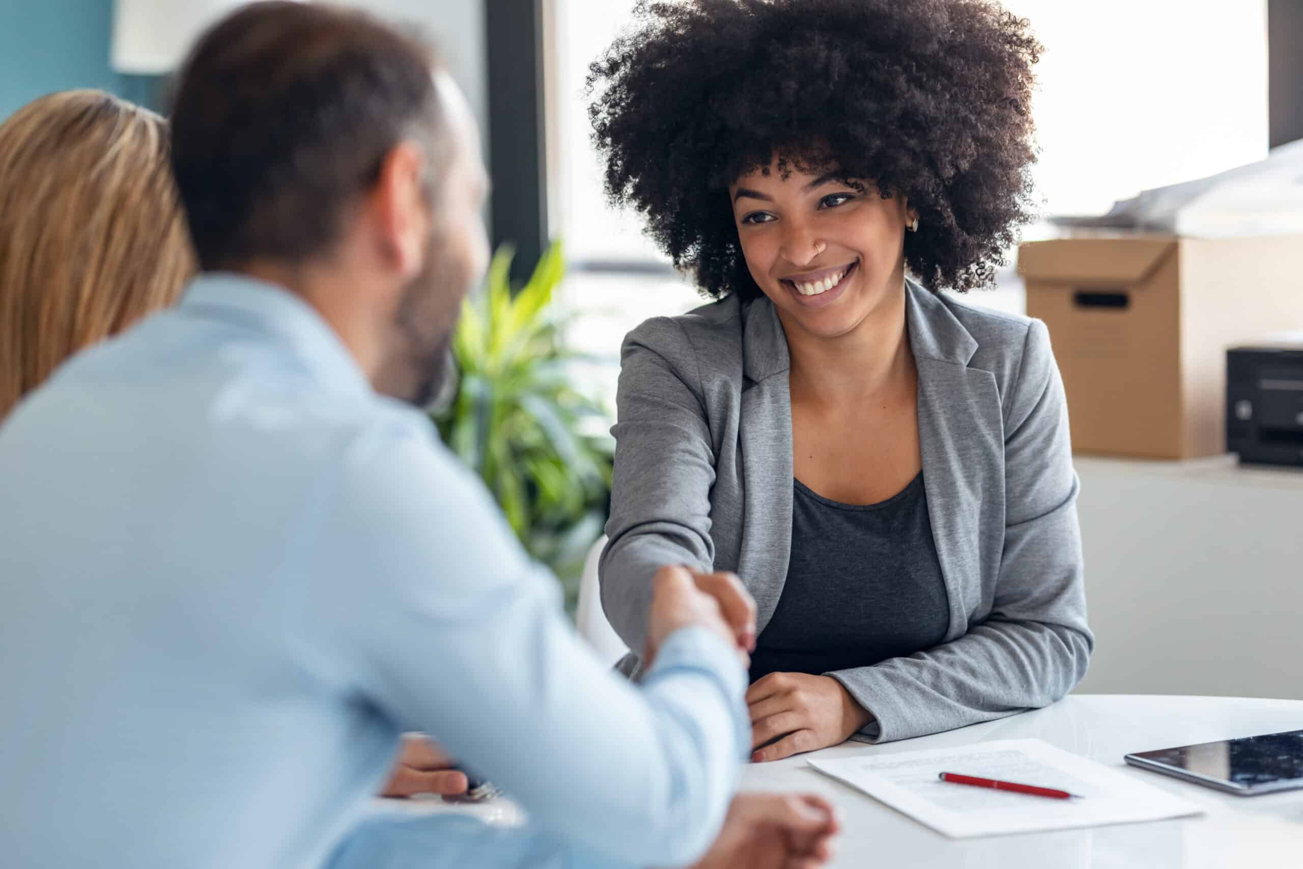 Woman with black hair shaking a man's hand.