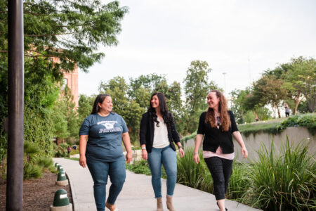 Three women walking down a concrete path