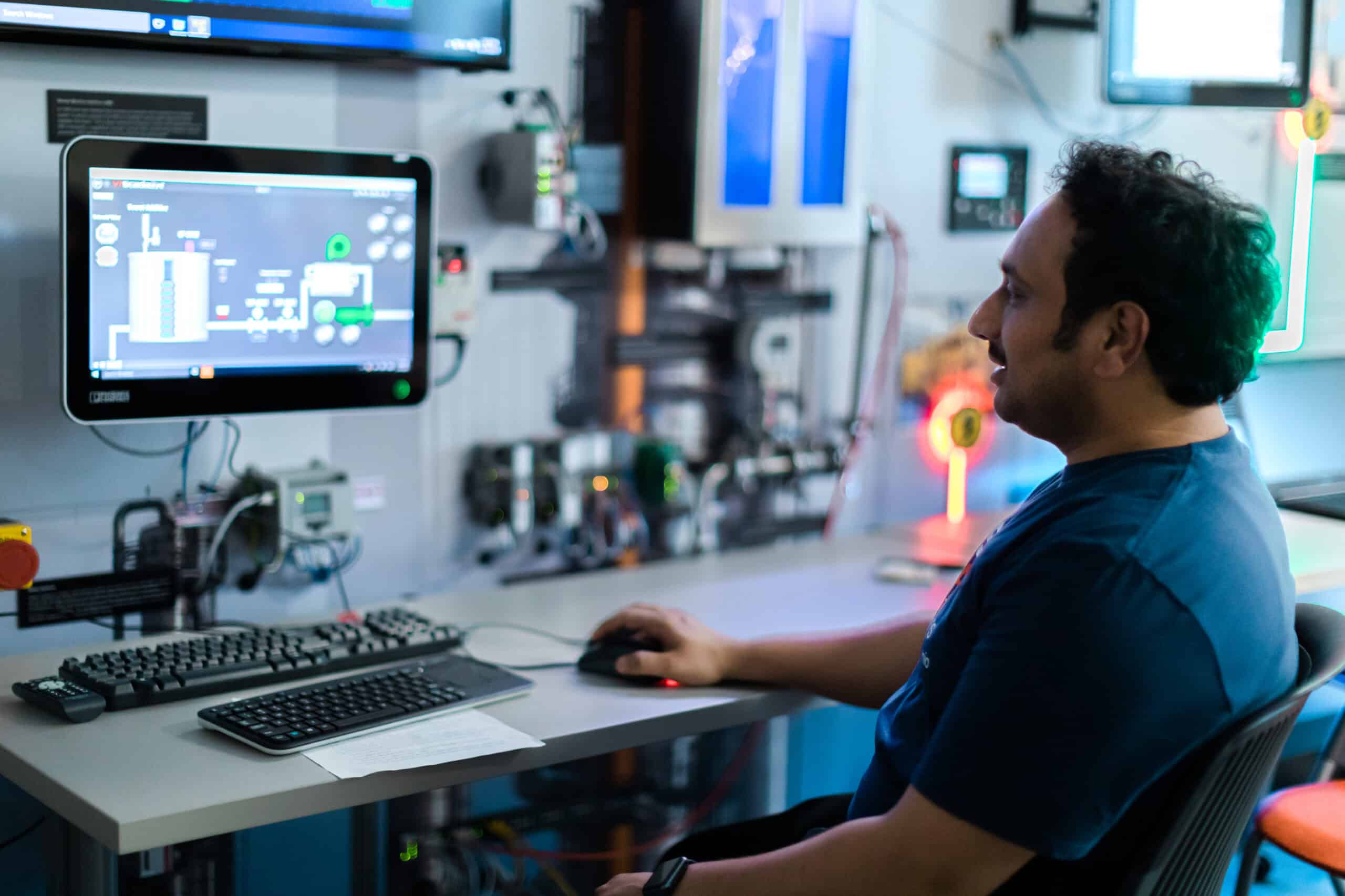 Man wearing a blue shirt looking at a computer screen in a lab.