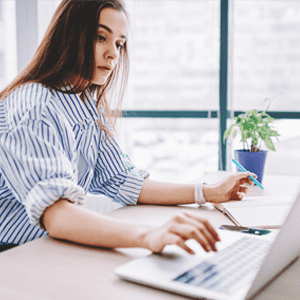 female online student working on her laptop with her notebook.