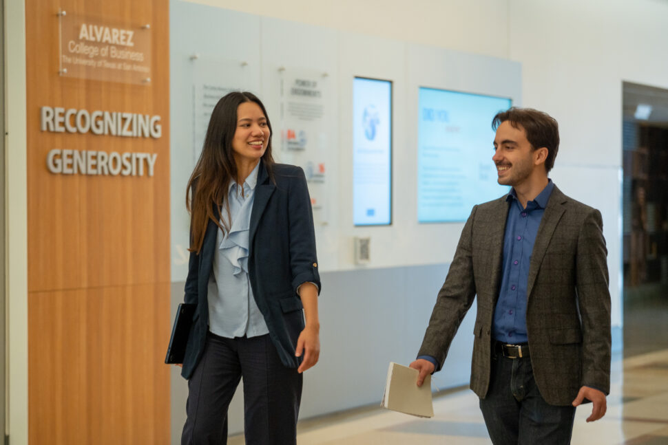 Man and woman walk through a hallway dressed in business casual attire.